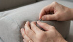 Close-up of hands testing the fabric and stitching quality of a sofa cushion